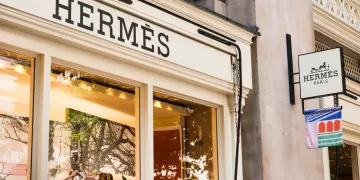Londres, Reino Unido, 13 de septiembre de 2024: Hermes frente a la tienda y escaparate. Ubicado en 1213 Royal Exchange, Londres EC3V 3LL. Distribuidor de gama alta que lleva la ropa, los bolsos y las bufandas de la marca de lujo.